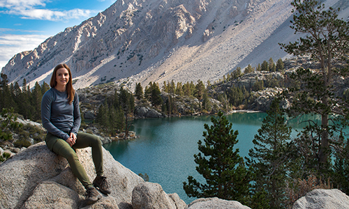 Christina sitting on rock in front of lake one on North Fork Lone Pine Creek Trail, CA